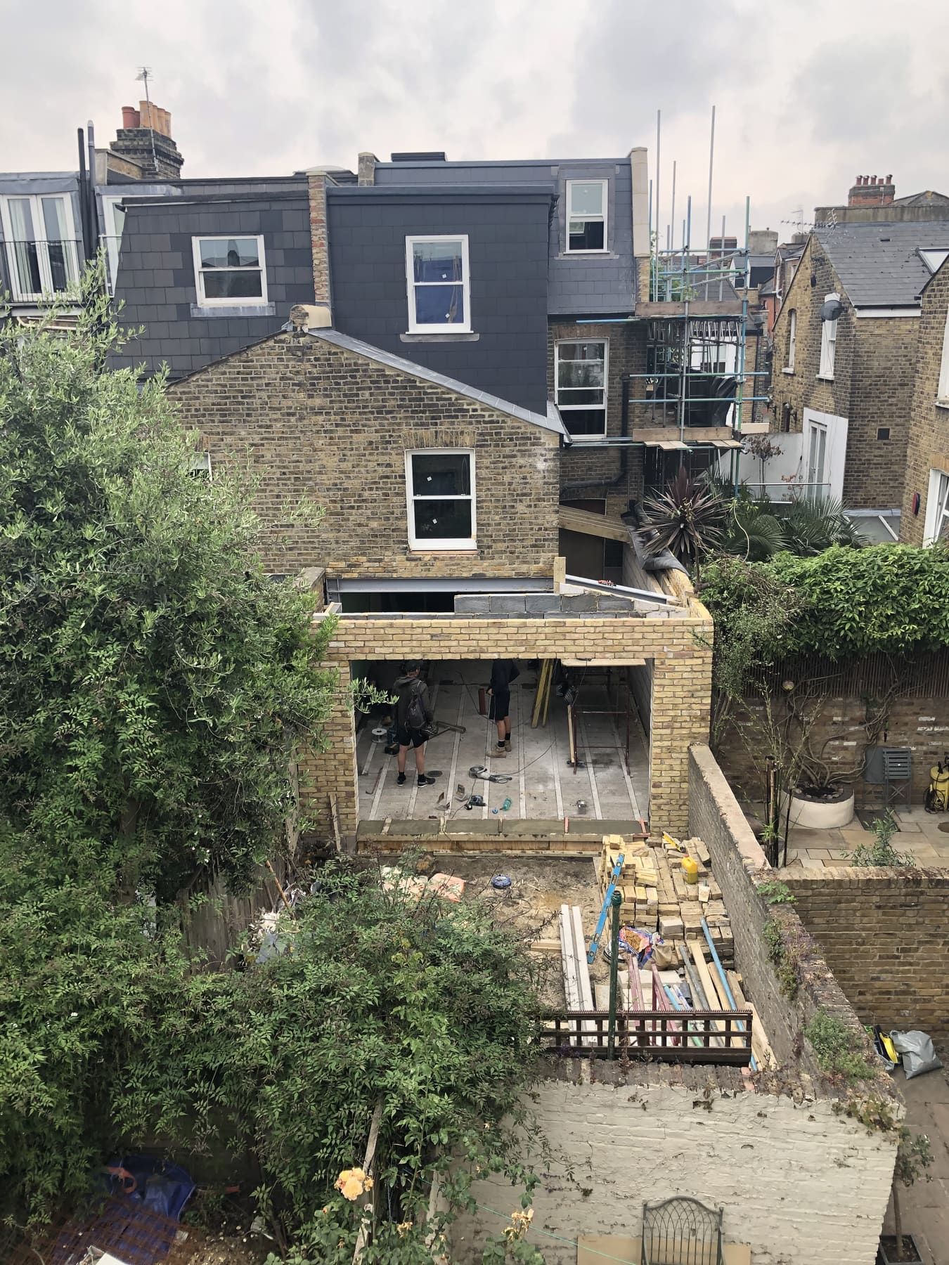 Brick shell of a rear extension under construction behind a Balham terrace, steels and blockwork in place