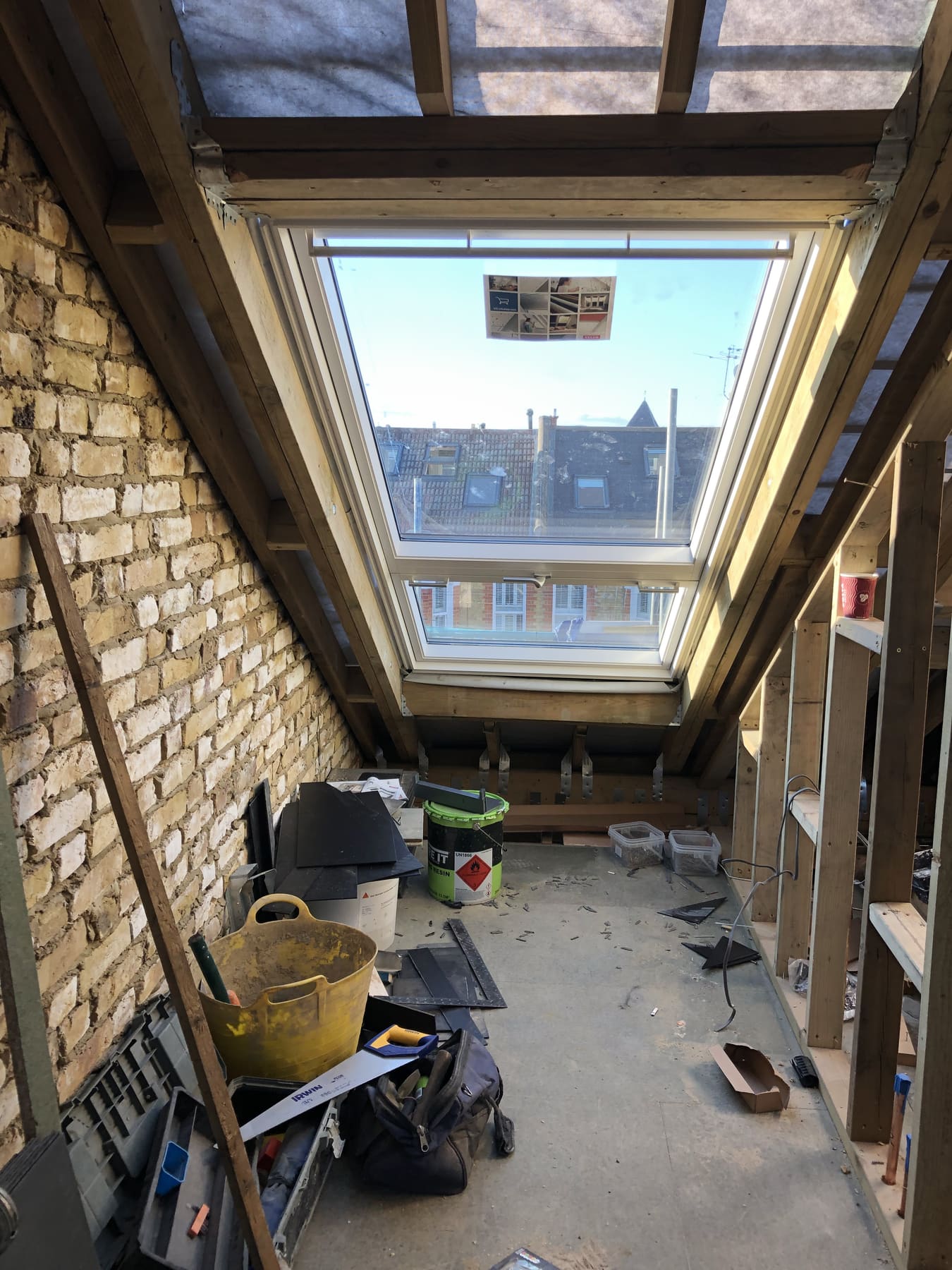 Loft interior during construction with a large roof window installed between new rafters