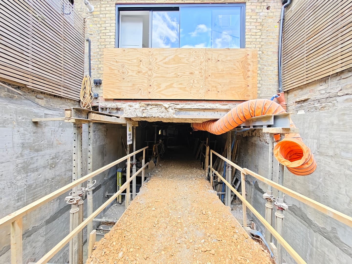 Basement excavation beneath a Clapham terrace with propping, ducting and an access ramp into the dig