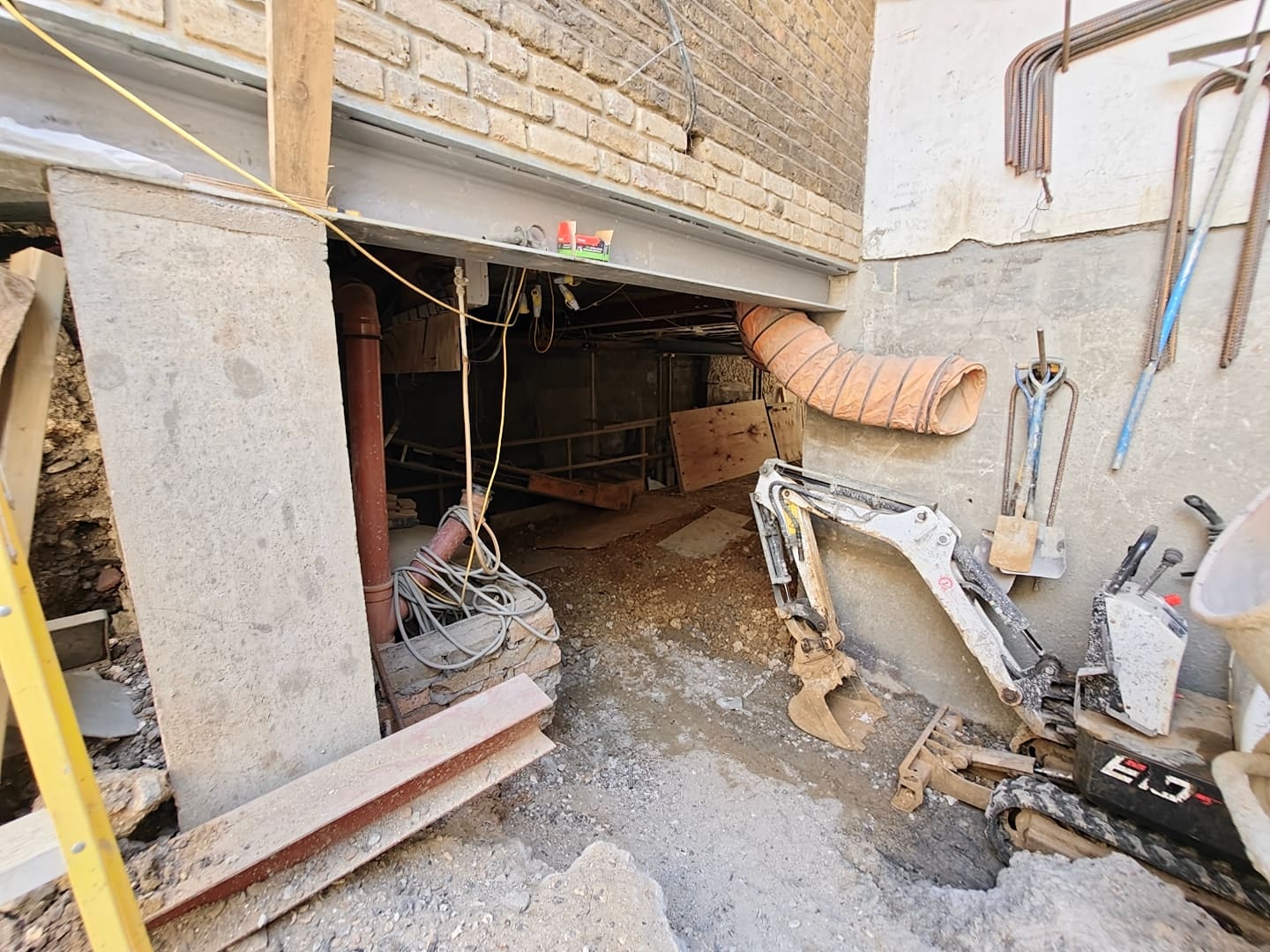 Mini excavator working in an underpinned basement beneath the existing structure