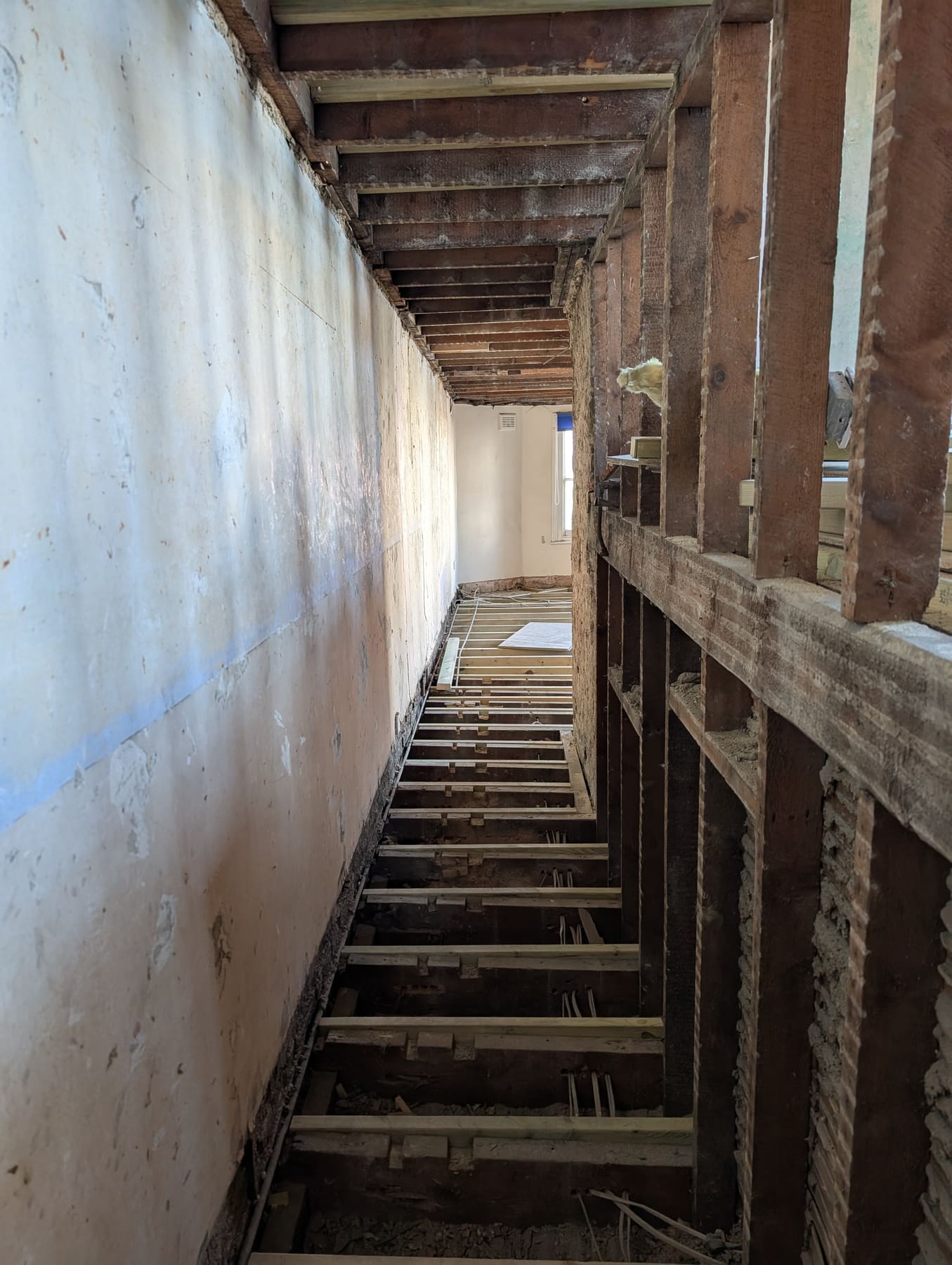 Stripped-out interior showing exposed floor joists and studwork